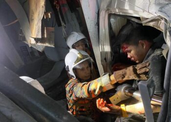 ANGGOTA Bomba dan Penyelamat berjaya mengeluarkan pemandu lori yang merempuh kedai kosong di Kampung Wakaf Raja, Pasir Puteh, Kelantan, hari ini. -UTUSAN/TOREKSULONG