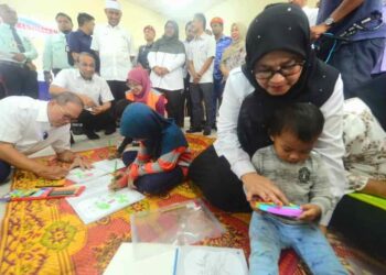 WAN ROSDY Wan Ismail (kiri) dan Pengerusi Jawatankuasa Kebajikan Masyarakat, Pembangunan Wanita dan Keluarga negeri, Datuk Sabariah Saidan (kanan) beramah mesra serta melayani anak-anak penduduk setempat sebagai simulasi ketika merasmikan Pusat Pemindahan Tetap (PPT) untuk mangsa banjir di Kampung Luit di Maran, Pahang. –  UTUSAN/SHAIKH AHMAD RAZIF