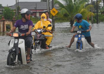 PENUNGGANG motosikal meredah banjir yang menenuhi jalan raya di Kuala Terengganu, baru-baru ini. - UTUSAN/PUQTRA HAIRRY ROSLI