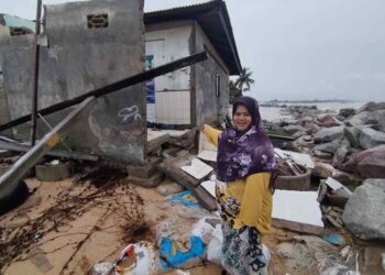 ZAINAB Zakaria menunjukkan sebahagian rumahnya yang roboh selepas dipukul ombak di Kampung Pengkalan Atap, Kuala Besut, Besut, semalam. – UTUSAN/WAN ZURATIKAH IFFAH WAN ZULKIFLI