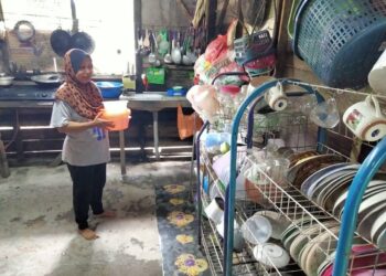 SUMAR YATI ZAINAL ABIDIN mengemas pinggan mangkuk bagi menghadapi musim banjir di rumahnya Jalan Kempas, Kampung Seri Gambut, Pekan Nanas, Pontian, semalam.