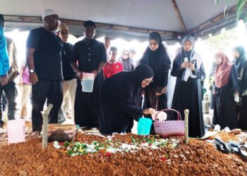 AHLI keluarga menyiram air dan menabur bunga di pusara Allahyarham di Tanah Perkuburan Masjid Al-Abrar, Semabok, Melaka. - UTUSAN/AMRAN MULUP