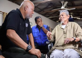 RAJA MOHAMED AFFANDI Raja Mohamed Noor (kiri) beramah mesra dengan seorang penduduk di Teluk Kalong di Kemaman, Terengganu. - UTUSAN/NIK NUR IZZATUL HAZWANI NIK ADNAN