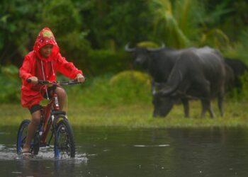 SEORANG kanak-kanak bermain banjir di halaman rumahnya di Kampung Alur, Surau Panjang, Kuala Terengganu, hari ini. - UTUSAN/PUQTRA HAIRRY ROSLI 