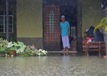 SEORANG penduduk melihat paras air di pekarangan rumahnya di  Kampung Alur, Surau Panjang, Kuala Terengganu, hari ini. - UTUSAN/PUQTRA HAIRRY ROSLI 
