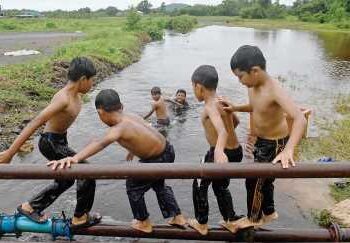 SEKUMPULAN kanak-kanak ceria bermain air di sebatang tali air di Kampung Teluk Paku, semalam. – UTUSAN/PUQTRA HAIRRY ROSLI.