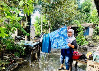 SASUHAIDA Sulaiman menjemur pakaian yang terendam akibat banjir berikutan cuaca cerah di Kuala Terengganu, hari ini. - UTUSAN/KAMALIZA KAMARUDDIN