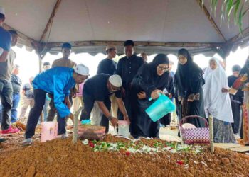 KELUARGA Allahyarham Abu Samah Abd Wahab menyiram air mawar di pusara beliau di Tanah Perkuburan Islam Kampung Semabok, Melaka, semalam. – UTUSAN/SYAFEEQ AHMAD