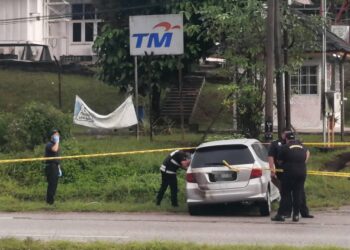 ANGGOTA polis memeriksa kereta sebuah kereta  berhampiran mayat wanita yang ditemukan di dalam longkang berhampiran Pejabat Kesihatan Daerah Hulu Terengganu, hari ini. - UTUSAN/NOOR HAYATI MAMAT
