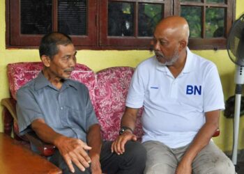 RAJA Mohamed Affandi (kanan) beramah mesra dengan seorang penduduk di Felda Kerteh 5, Kemaman, hari ini. - UTUSAN/NIK NUR IZZATUL HAZWANI NIK ADNAN