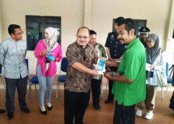 SHAMSUL Iskandar Mohd. Akin (kiri) menyampaikan sumbangan kepada mangsa ribut di Ipoh hari ini. - UTUSAN/FADZIL ZAINOL