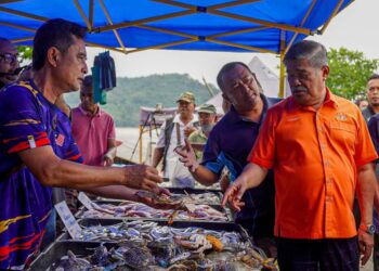 MOHAMAD Sabu (kanan) meninjau nelayan yang menjual hasil tangkapan laut di Kompleks LKIM, Kuala Kemaman, Kemaman, hari ini.