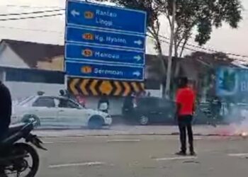 TANGKAP layar sebuah video tular memaparkan beberapa individu memberhentikan kenderaan dan membakar mercun di atas jalan raya di Kuala Sawah, Rantau di sini semalam.