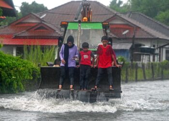 Penduduk Kampung Atas Tol, Kuala Terengganu menumpang jentolak  berikutan jalan dinaiki air, semalam. -UTUSAN/PUQTRA HAIRRY