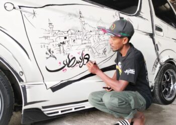 MOHD. Rozamil Mohd. Yatim menghasilkan lukisan tema Palestin di sebuah kenderaan di Chendering, Kuala Terengganu, semalam. - UTUSAN/KAMALIZA KAMARUDDIN