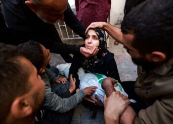 BEBERAPA orang cuba menenangkan seorang wanita memegang mayat bayi perempuannya yang terbunuh dalam serangan Israel di Rafah di selatan Semenanjung Gaza.-AFP