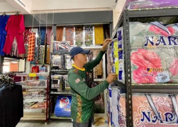 YAZE Salleh menyusun barang di lot niaganya di Kompleks Darul Qiyyam, Bukit Kayu Hitam di Kubang Pasu. -UTUSAN/JAMLIAH ABDULLAH