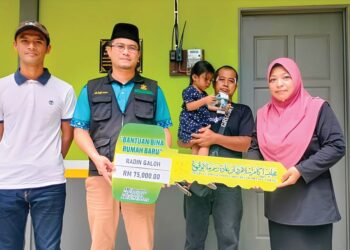 HASMAH Yaakob (kanan) menerima replika kunci daripada Mohd. Faitullah Saadon (dua dari kiri) rumah baharu sumbangan Majlis Ugama Islam dan Adat Resam Melayu Pahang (Muip) di Kampung Teluk Ira di Temerloh, Pahang.