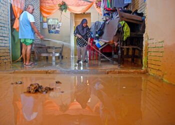 PENDUDUK membersihkan rumah mereka yang dipenuhi lumpur selepas dilanda banjir di Kampung Tok Kah, Dungan, Terengganu, semalam. - UTUSAN/PUQTRA HAIRRY