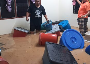 DUA penduduk menyelamatkan peralatan rumah yang mula dinaiki air banjir di Kampung Pamah Rawas di Raub, Pahang. - FOTO/IHSAN PENDUDUK PAMAH RAWAS