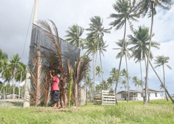 ASMAWI Mahmud menyusun pelepah kelapa untuk dijadikan penghadang bagi melindungi rumahnya daripada tiupan angin kencang pada musim tengkujuh di Kampung Jambu Bongkok, Marang. - UTUSAN/PUQTRA HAIRRY ROSLI