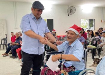 SHAHELMEY Yahya (kiri) menyampaikan bantuan kepada salah seorang penduduk Kampung Potuki di Putatan semalam.