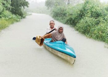 ROHANI Ismail bersama Daud Che Mat menaiki kayak meredah banjir untuk menyelamatkan lembu peliharaan mereka di Kampung Mak Bakas, di Pelong, Setiu, Terengganu. - UTUSAN/WAN ZURATIKAH IFFAH WAN ZULKIFLI