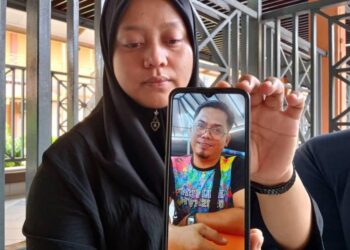 NORLINDA Jamil menunjukkan gambar Halmi Tahrin yang maut disengat tebuan tanah di Hutan Simpan di Jalan Temayong Labis, Segamat, Johor, semalam.