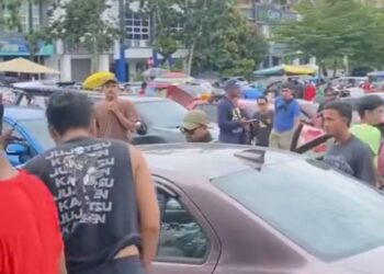 TANGKAP layar daripada sebuah video yang tular menunjukkan orang ramai berkumpul di sekeliling kereta bagi melihat mayat di tapak jualan but kereta di Damansara. - MEDIA SOSIAL