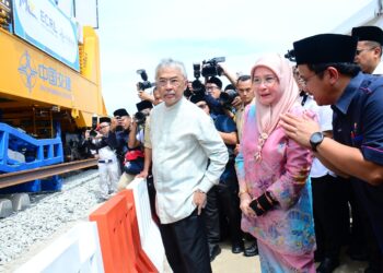 AL-SULTAN ABDULLAH Ri'ayatuddin Al-Mustafa Billah Shah (kiri) dan Tunku Azizah Aminah Maimunah Iskandariah (tengah) mencemar duli melihat dengan lebih dekat mesin membina landasan bagi projek Laluan Rel Pantai Timur (ECRL) di Gebeng di Kuantan, Pahang. - UTUSAN/SHAIKH AHMAD RAZIF