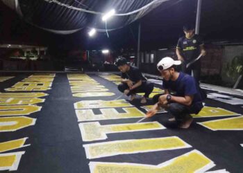 AHLI kelab penyokong Geng 12 bergotong-royong menyiapkan kain rentang bersaiz gergasi bagi memberi sokongan kepada TFC di Stadium Nasional Bukit Jalil, esok. - UTUSAN/TENGKU DANISH BAHRI TENGKU YUSOFF