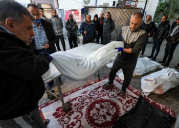 Anggota perubatan mengangkat jenazah mangsa serangan bom Israel di luar Hospital al-Najjar di Rafah semalam. – AFP