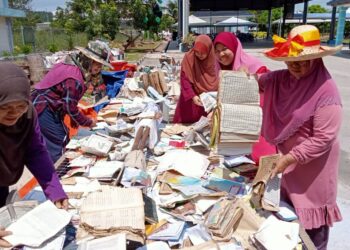 SUKARELAWAN memeriksa dan mengasingkan helaian kitab suci yang terjejas dan rosak akibat banjir yang lalu di Pusat Pelupusan Al-Quran di Masjid Taman Yayasan, Segamat.