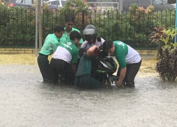 BEBERAPA pelajar membantu mengalihkan motosikal daripada ditenggelami banjir di Maktab Sultan Abu Bakar, Jalan Sungai Chat, Johor Bahru.