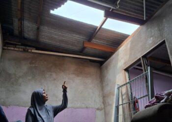 HAYATI Mukhtar menunjukkan sebahagian bumbung rumahnya yang rosak dalam kejadian ribut di Taman Melor, Kampung Pengkalan Pandan, Chukai, Kemaman, hari ini. - UTUSAN/NIK NUR IZZATUL HAZWANI NIK ADNAN