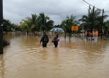 DUA penduduk meredah banjir di PPSK Felcra Gunung Menerong, Hulu Terengganu, hari ini. - UTUSAN/NOOR HAYATI MAMAT