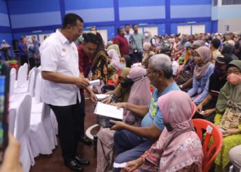 ABDUL RAHMAN Mohamad (kiri) menyampaikan bantuan kewangan kepada golongan asnaf sempena program CSR Lembaga Lebuhraya Malaysia di Lipis, Pahang. - UTUSAN/ SALEHUDIN MAT RASAD