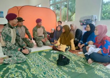 MOHD. Zaki Jusoh (kiri) beramah mesra dengan mangsa banjir yang dipindahkan di PPS Pengkalan Ajal, Ajil, Hulu Terengganu, hari ini. - UTUSAN/NOOR HAYATI MAMAT