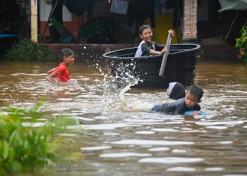 SEKUMPULAN kanak-kanak bermain banjir  di Kampung Paya, Balai Besar, Dungun, semalam. - UTUSAN/PUQTRA HAIRRY ROSLI