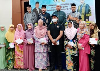WAN Mohd. Zakri Wan Mohd. (belakang, dua dari kiri) dan Maliaman Kassim (belakang, dua dari kanan) bersama sebahagian 21 ibu tunggal yang menerima bantuan pendahuluan nafkah di Kuala Terengganu, hari ini. - UTUSAN/KAMALIZA KAMARUDDIN