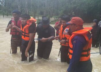 PEMUDA OKU (dua kiri) selepas berjaya diselamatkan oleh anggota pasukan penyelamat di Kampung Buchik, Machang, Kelantan petang tadi.