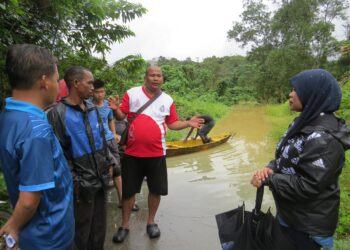 ZARINA Razlan (kanan) meninjau keadaan laluan yang masih terjejas akibat air banjir yang bertakung di Kampung Pasir Linggi, Pos Lebir, Gua Musang, Kelantan semalam-UTUSAN/AIMUNI TUAN LAH.