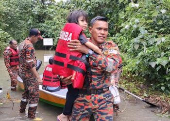 ANGGOTA bomba membantu membawa salah seorang anak mangsa banjir ke klinik selepas terperangkap dalam banjir di Kampung Paya Kemudi, Dungun, hari ini. - UTUSAN/NIK NUR IZZATUL HAZWANI NIK ADNAN