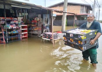 SEORANG peniaga kedai tetap menerusi operasi walaupun premisnya di tenggelami banjir di Meranti, Pasir Mas, Kelantan semalam-UTUSAN/ROHANA ISMAIL.