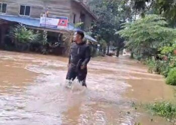 SEORANG penduduk meredah banjir selepas air Sungai Dungun melimpah di Kampung Pasir Raja, Dungun, petang tadi. - UTUSAN/NIK NUR IZZATUL HAZWANI NIK ADNAN