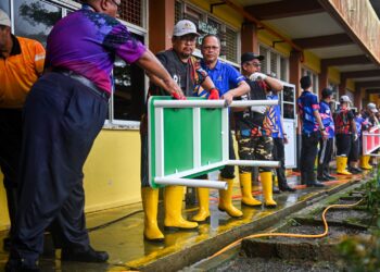 ANGGOTA sukarelawan Kementerian Pendidikan bergotong-royong membersihkan SK Sungai Las, Setiu yang terjejas banjir, hari ini. - UTUSAN/PUQTRA HAIRRY ROSLI