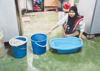 NUR SYAFIQAH Mohd. Kamil menyusun beberapa bekas bagi menadah air hujan yang memasuki rumahnya di Jalan Pejabat, Bandar Pontian, Pontian, Johor. - UTUSAN/MUHAMMAD ZIKRI