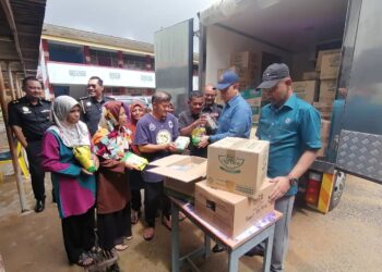 SAHARUDDIN Mohd. Kia (dua dari kanan) menyampaikan sumbangan barangan makanan kepada mangsa banjir di SMK Menerong, Hulu Terengganu, hari ini. - UTUSAN/NOOR HAYATI MAMAT