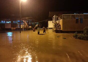 PEMILIK kedai kopi dan makanan sedang memantau premis yang mula dilimpahi air Sungai Tembeling di Kampung Bantal, Ulu Tembeling di Jerantut, Pahang. - FOTO/HARIS FADILAH AHMAD