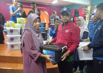 PENYELARAS Dewan Undangan Negeri (DUN) Pulau Tawar, Haris Salleh Hamzah (dua dari kanan) menyampaikan bantuan makanan kerajaan negeri kepada seorang mangsa banjir di PPS Sekolah Kebangsaan (SK) Felda Kota Gelanggi 1 di Jerantut, Pahang. - FOTO/HARIS FADILAH AHMAD
